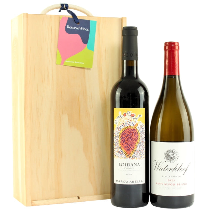 Two wine bottles, one red and one white, in front of a wooden gift box with Reserve Wines tag.