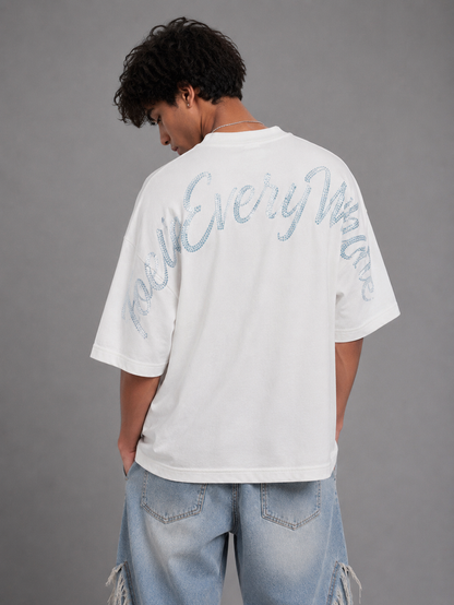 White oversized rhinestone T-shirt by Inner Peace with "Peace Everywhere" slogan, featuring sparkling embellishments.