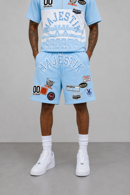 Light blue Majestik Champion rhinestone rugby patched shorts, stylish casual shorts with decorative patches and rhinestone details.