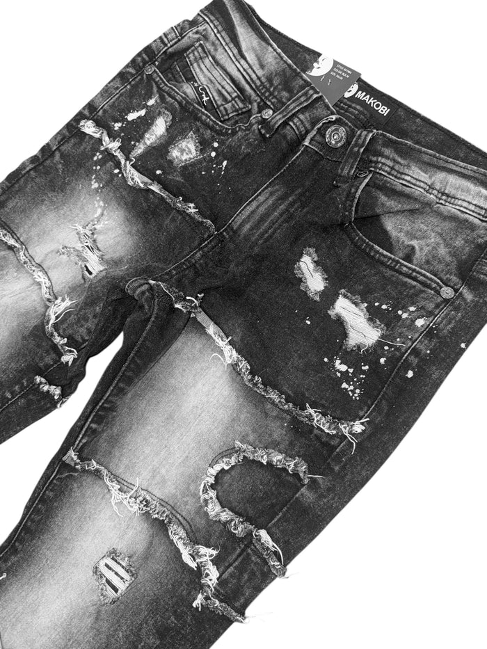 Makobi Pastoni stacked denim jeans in black wash with a slim fit and layered design, displayed on a hanger.